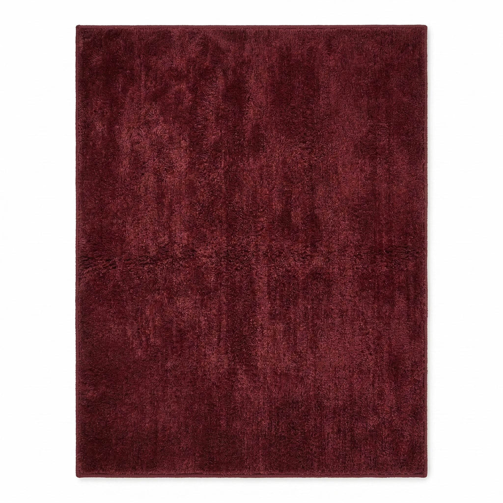 Plush solid burgundy hand-tufted wool rug showcasing a dense, luxurious cut pile texture on a clean white background.