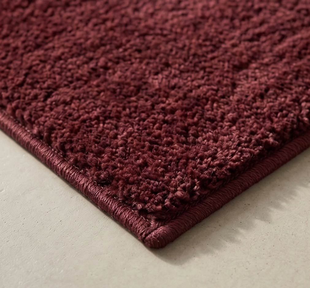 Plush solid burgundy hand-tufted wool rug showcasing a dense, luxurious cut pile texture on a clean white background.