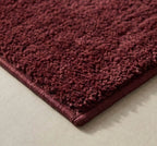 Plush solid burgundy hand-tufted wool rug showcasing a dense, luxurious cut pile texture on a clean white background.