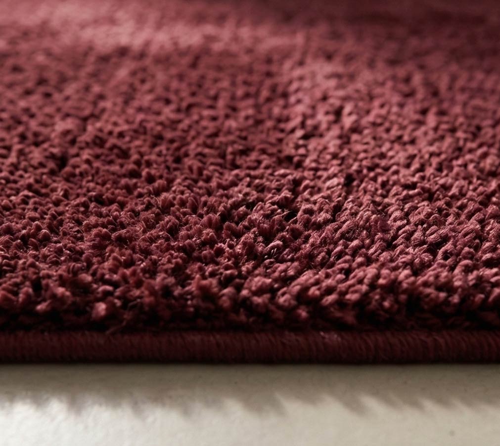 Plush solid burgundy hand-tufted wool rug showcasing a dense, luxurious cut pile texture on a clean white background.
