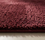 Plush solid burgundy hand-tufted wool rug showcasing a dense, luxurious cut pile texture on a clean white background.